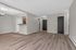 Modern apartment interior with sleek wood flooring, open-concept layout, and a view of a stylish kitchen with stainless steel appliances.