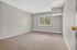Bright, spacious bedroom with large window, offering abundant natural light and serene views. Freshly painted walls and cozy carpet flooring enhance comfort.
