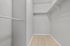 Spacious walk-in closet with sleek hanging rails and tiled flooring, perfect for organized living.