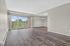 Bright and airy living room with large sliding glass doors opening to a scenic balcony, featuring modern wood flooring and elegant pendant lighting.