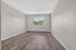 Bright and inviting room with elegant wooden flooring and a large window offering a serene view of lush greenery.