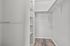 Spacious walk-in closet with sleek shelves and modern wood flooring, perfect for organized living.