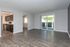 Spacious living room with elegant dark wood flooring, open kitchen, and large sliding glass doors leading to a sunlit balcony.