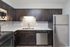 Contemporary kitchen with sleek dark cabinetry, stainless steel appliances, and stylish tile backsplash.