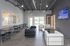 Modern community lounge with sleek black and white sofas, chic dining area, and large screen TV, inviting ample natural light through the glass doors.