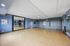 Spacious and versatile blue-walled room with large mirrors, perfect for yoga or dance activities, featuring stylish lighting and polished wooden floors.