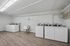 Modern laundry room with multiple washing machines and a utility sink, featuring elegant hardwood flooring and bright overhead lighting.