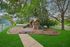 Charming outdoor playground with slides and wooden structures surrounded by lush greenery and peaceful fencing.