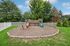 Charming outdoor playground surrounded by lush greenery, featuring a wooden playset with a slide and climbers, perfect for family fun.