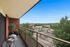 Charming balcony view showcasing lush greenery and a serene parking area, perfect for relaxing outdoor moments.