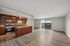 Modern open-concept apartment with sleek kitchen featuring granite countertops, stylish backsplash, and stainless steel appliances adjacent to a spacious living area with large sliding glass doors offering scenic views.