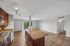 Spacious open-plan kitchen and living area featuring elegant granite countertops, modern lighting, and stylish wood floors with scenic balcony view.