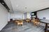 Modern community room with elegant round tables, stylish wooden chairs, and a wall-mounted TV, ideal for gatherings and meetings.