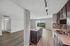 Modern open-concept apartment kitchen with sleek cabinetry, granite countertops, and stunning hardwood floors leading to a bright living area with panoramic views.