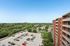 Stunning high-rise view showcasing a spacious parking lot, lush green surroundings, and serene neighborhood landscape.