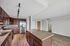 Modern kitchen with elegant dark wood cabinetry, gleaming stainless steel appliances, and granite countertops, seamlessly connecting to a bright living area with wooden floors.