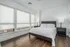 Bright, modern bedroom with large windows, elegant hardwood floors, and cozy lighting.