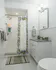 Charming bathroom featuring a stylish shower with a vibrant lemon-themed curtain, elegant tile flooring, and sleek white cabinetry.
