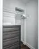 Elegant, organized closet space featuring clean white shelves, minimalist hangers, and a stylish dark wood dresser, ideal for modern living.