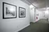 Elegant hallway with modern white walls and classic black-framed photographs, featuring cozy carpet flooring and inviting doorways.