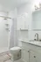 Elegant bathroom featuring a marble countertop, modern faucet, and spacious walk-in shower with white tile accents.