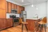 Modern kitchen with sleek stainless steel appliances, warm wooden cabinetry, and elegant granite countertops, complemented by stylish pendant lighting and comfortable barstools at the island.