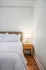 Cozy bedroom corner featuring a plush bed with crisp white linens and a stylish bedside table with a modern lamp.