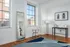 Bright and modern room featuring large windows, elegant full-length mirror, chic artwork, and stylish wooden floor.