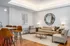 Modern living room with stylish decor featuring a cozy beige sofa, sleek round mirror, and elegant leather chairs around a contemporary kitchen island.