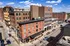 Vibrant urban street view showcasing charming historic brick buildings under a clear blue sky, perfect for city living with a touch of classic elegance.