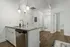 Chic modern kitchen with sleek granite countertops, stainless steel appliances, and warm wood flooring, leading to a pristine bathroom and cozy living space.