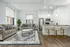 Elegant modern living space featuring cozy sofas, a stylish blue-patterned rug, and a bright kitchen with luxurious bar seating.