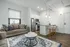 Modern apartment interior featuring a cozy living area with elegant furniture, a stylish rug, and an open-concept kitchen equipped with stainless steel appliances and chic bar stools.
