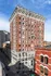 Elegant red-brick apartment building with intricate architectural details, offering a classic urban charm in a bustling cityscape.