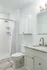 Elegant bathroom with a marble countertop, modern fixtures, and a spacious walk-in shower featuring subway tiles.