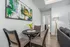 Contemporary dining space with chic seating, vibrant abstract art, and a cozy ambiance in a modern apartment.