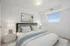 Inviting bedroom with a plush bed, abstract artwork, and natural light from a large window.