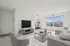 Inviting living room with sleek furniture, large windows, and a TV on a modern console.