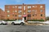 Front view of a classic brick apartment building with multiple windows and a red awning entrance.