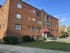 Exterior view of a traditional red brick apartment building with large windows and a welcoming entrance.