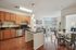 Inviting open-concept apartment with a modern kitchen and cozy living area, featuring stylish pendant lighting and large windows offering abundant natural light.