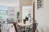Bright and inviting apartment featuring a cozy dining area and open doorway to a chic bedroom, with large windows and modern decor.
