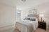Elegant bedroom with a cozy bed, plush pillows, and modern decor, bathed in natural light from a large window.