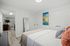 Inviting bedroom with modern decor, featuring a cozy bed, vibrant artwork, and ample storage space in a fresh and bright setting.