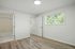Bright and airy bedroom with elegant wood flooring, large window offering scenic view, and en-suite bathroom.