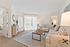 Bright and inviting living room with plush beige sofas, modern decor, and natural light streaming through large windows.