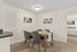 Elegant dining area with contemporary art, featuring a cozy table setting for four, leading into a serene bedroom space.