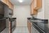 Modern kitchen with sleek black appliances, stylish granite countertops, and ample wooden cabinetry, offering a sophisticated cooking space.