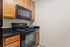 Modern kitchen with sleek black appliances, granite countertops, and elegant wooden cabinetry, perfect for culinary enthusiasts.