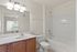 Bright and modern bathroom featuring a clean white vanity, sleek mirror with contemporary lighting, cozy bathtub, and large window for natural light.